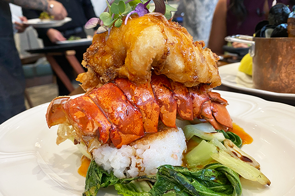 Fried lobster tail on top of a red lobster shell on top of a bed of rice with greens | 127 Peachtree Rd NE, Atlanta, GA 30303