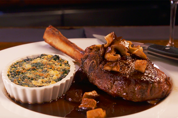This succulent veal chop is called “cotoletta.” It is served with the bone in and has mushrooms and a generous pour of demi glace on top. Creamed spinach is served on the side to perfectly complement the meat.