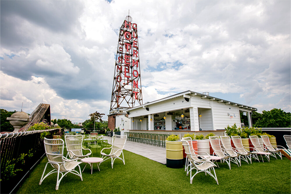 Rooftop bar with turf on the ground, several white chairs, and a white building with a tall structure reading "Hotel Clermont" in red letters | 789 Ponce De Leon Ave NE, Atlanta, GA 30306