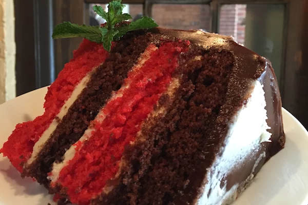 A close-up of a large slice of cake with white, brown, and red layers | 174-184 W Clayton St, Athens, GA 30601