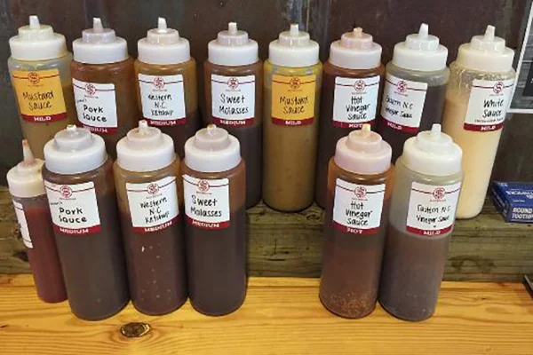 Two rows of bottles of BBQ sauce with various labels and colors | 830 W Broad St, Athens, GA 30601