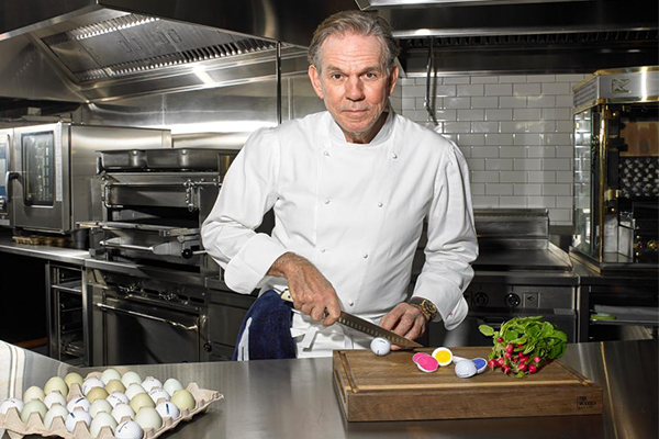 Chef Thomas Keller cutting what appears to be a golf ball while standing in a kitchen