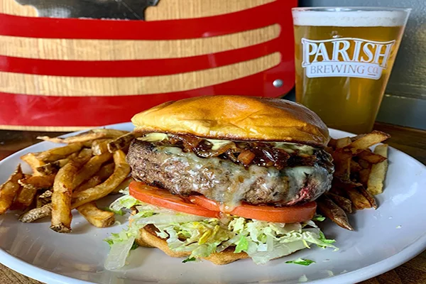 A cheeseburger with caramelized onions, tomato, cheese, lettuce, and tomato with fries and a glass of beer behind it | 269 N Hull St, Athens, GA 30601