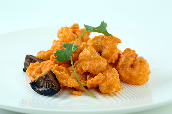 Pile of fried and sauced shrimp with a green garnish 